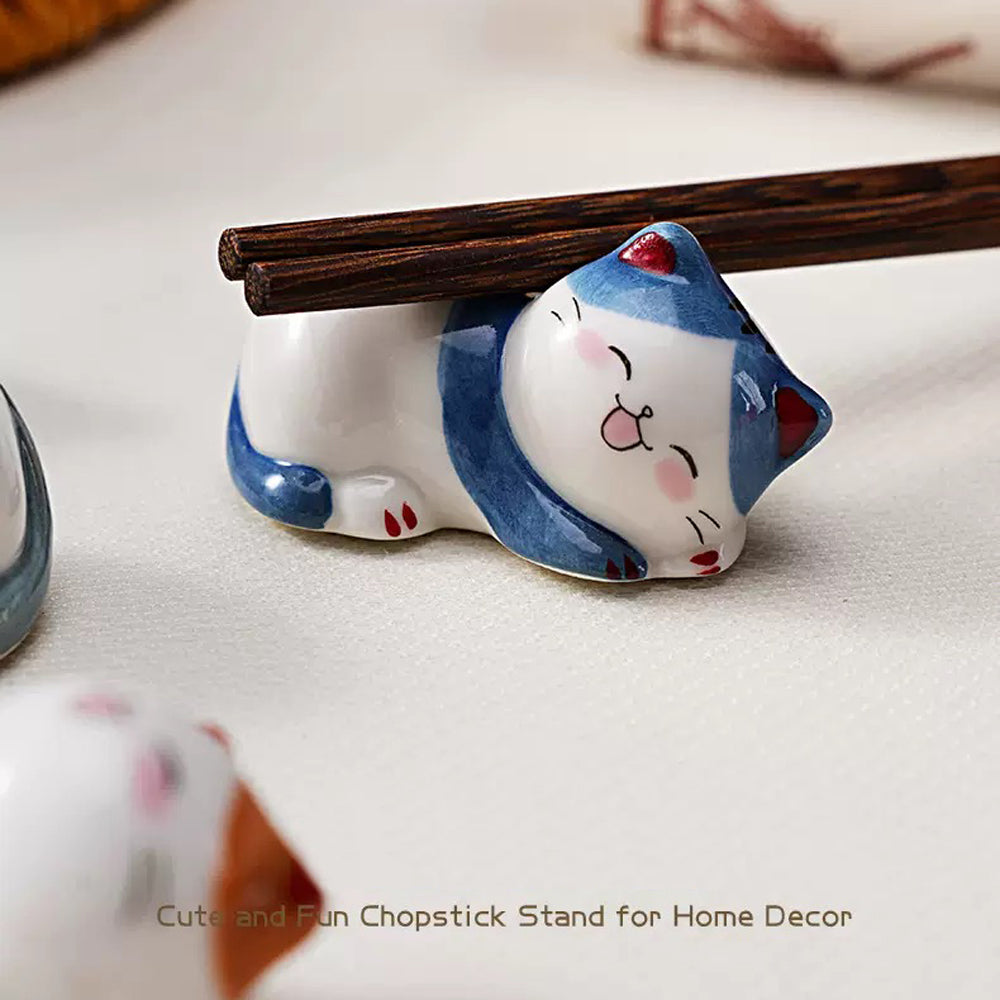 Ceramic cat chopstick rests holding chopsticks, forks, spoons, and paint brushes on dining table