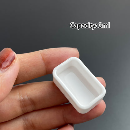 Hand holding a ceramic full pan 3ml, empty watercolor container for handmade paints and DIY palettes