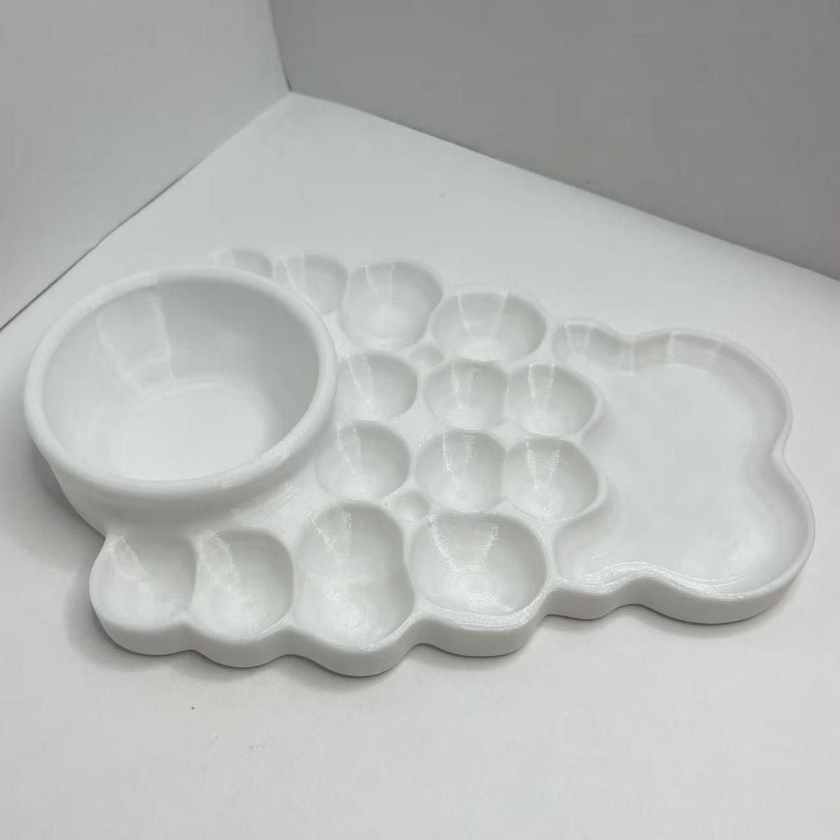 Minimalist plastic artist palette combining multiple paint wells, smooth mixing surfaces, and a built-in water bowl