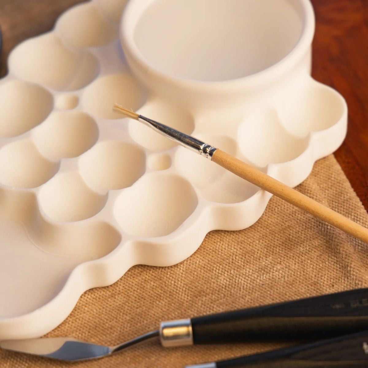 Plastic watercolor mixing palette with separate paint wells and a built-in water bowl for watercolor painting
